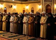 Ilustrasi suasana masjid yang tenang dan khusyuk pada waktu malam, dengan jamaah sedang melaksanakan shalat Isya berjamaah, melambangkan ketenangan spiritual dan janji pahala besar dari Allah SWT di penghujung hari.