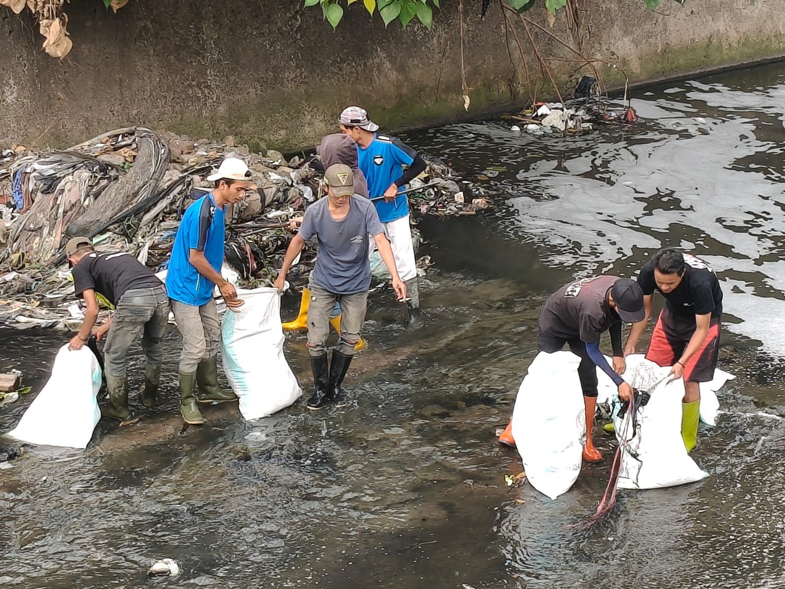 Warga RW 16 Citeureup bergotong royong membersihkan endapan lumpur dan sampah di saluran air bersama Tim Pentahelix Dayeuhkolot.